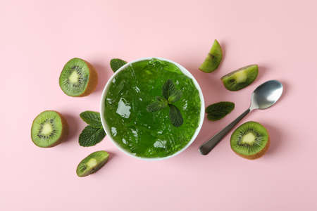 Bowl of kiwi jelly, kiwi slices, spoon and mint on pink backgroundの写真素材