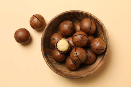 Bowl with tasty macadamia nuts on beige backgroundの写真素材