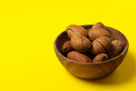 Bowl with tasty pecan nuts on yellow backgroundの写真素材