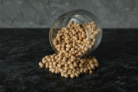 Glass jar with chickpea on black smokey tableの写真素材