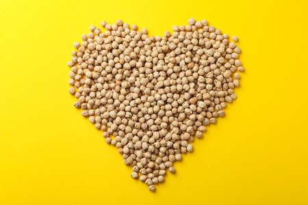 Heart made of chickpea on yellow backgroundの写真素材
