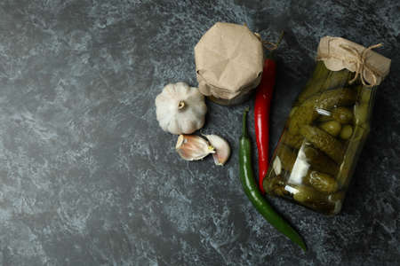 Jar of pickled cucumbers and ingredients on black smokeyの写真素材