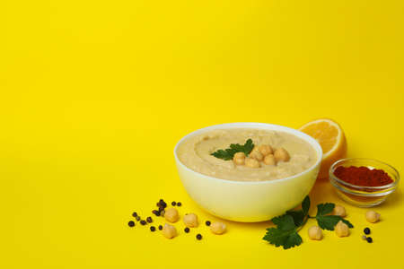 Bowl of hummus and ingredients on yellow backgroundの写真素材