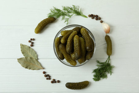 Bowl with pickled cucumbers and ingredients on white wooden backgroundの写真素材