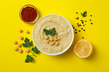 Bowl of hummus and ingredients on yellow backgroundの写真素材