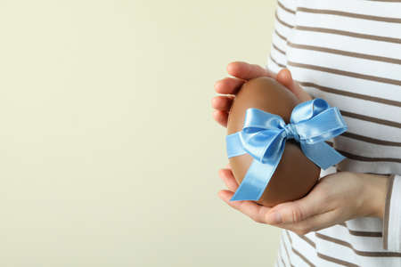 Woman hold chocolate egg with blue ribbon, space for textの写真素材