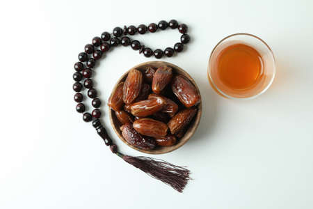 Glass of tea, bowl of dates and rosary on white backgroundの写真素材