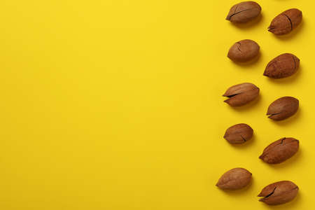Tasty pecan nuts on yellow background, space for text and top view