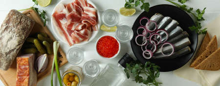 Shots of vodka and tasty snacks on white wooden table, top viewの写真素材