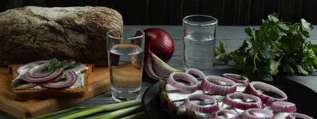 Shots of vodka and tasty snacks on wooden tableの写真素材