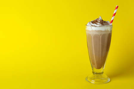 Glass of chocolate milkshake with straw on yellow backgroundの写真素材