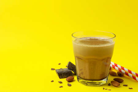 Chocolate milkshake, almond, chocolate and straws on yellow backgroundの写真素材