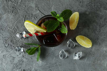 Glass of Cuba Libre and ingredients on gray table