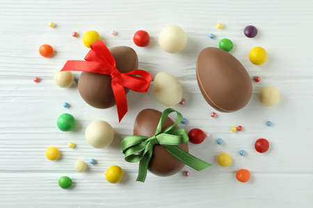 Easter chocolate eggs and candies on white wooden table