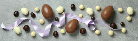 Easter chocolate eggs and candies on gray background