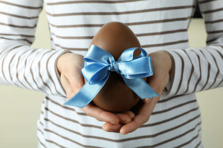 Woman hold chocolate egg with blue ribbon, close upの写真素材