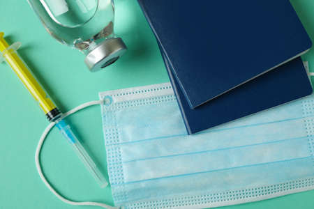 vaccine, syringe, mask and passports on mint backgroundの写真素材