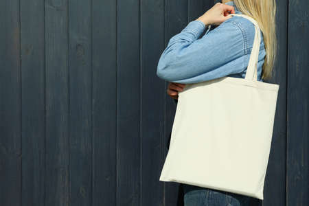Young woman with stylish eco bag on wooden backgroundの写真素材