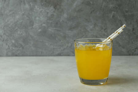 Glass of orange soda on white textured table against gray background