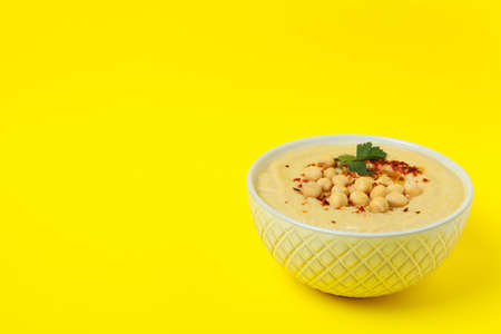 Bowl of fresh hummus on yellow backgroundの写真素材