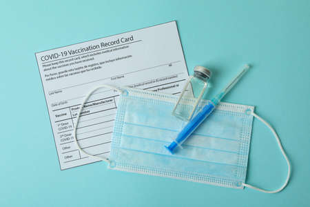 Vaccination record card, mask and syringe on blue backgroundの写真素材