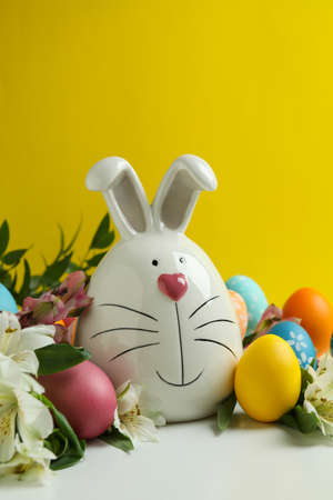 Easter bunny, eggs and alstroemeria flowers against yellow background
