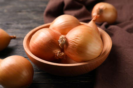 Bowl with fresh onion and kitchen towel on wooden backgroundの写真素材