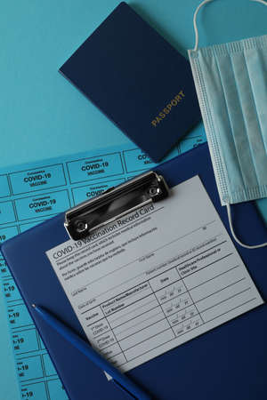 vaccination concept with record card, mask and passport on blue background