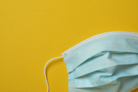 Medical mask on yellow background, space for textの写真素材
