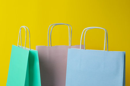 Blank colorful paper bags on yellow backgroundの写真素材