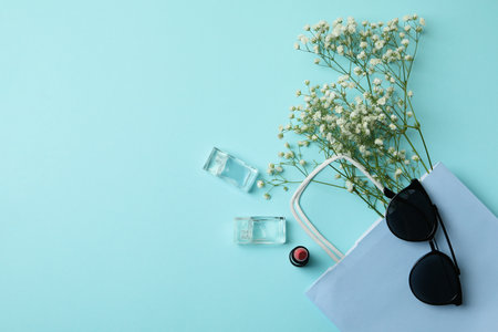 Bag, sunglasses, perfumes, lipstick and flowers on blue backgroundの写真素材