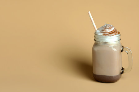 Glass of chocolate milkshake with straw on beige backgroundの写真素材