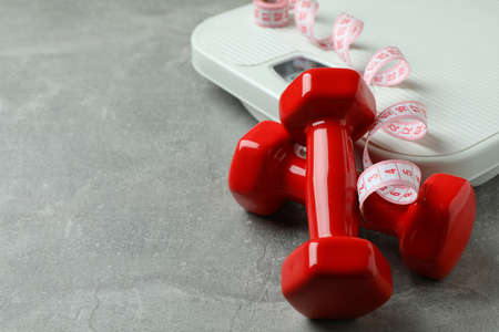 Scales, dumbbells and measuring tape on gray backgroundの写真素材