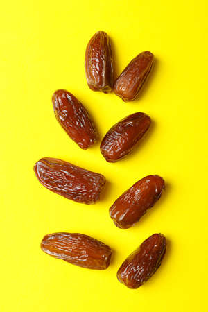 Tasty dried dates fruits on yellow background