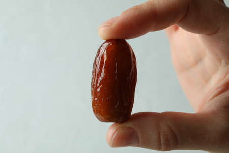 Female fingers hold date fruit, close upの写真素材