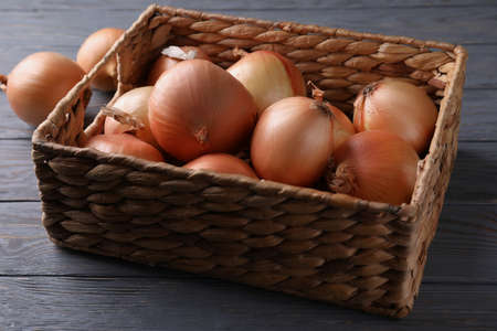 Basket with fresh onion on wooden backgroundの写真素材