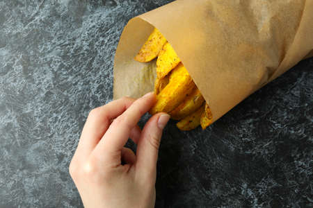Female hand take potato from paper bag