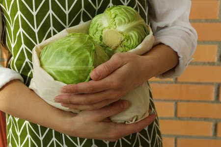 Woman hold fresh green cabbage against brick wallの写真素材