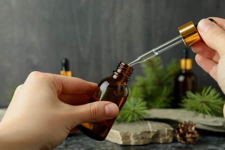 Female hands hold pipette and bottle with pine oil