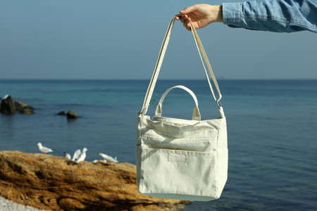 Female hand hold stylish eco bag against seaの写真素材