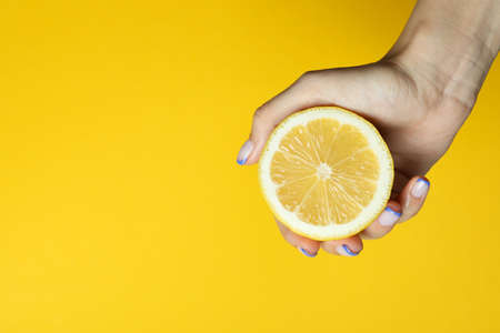 Female hand hold lemon on yellow backgroundの写真素材