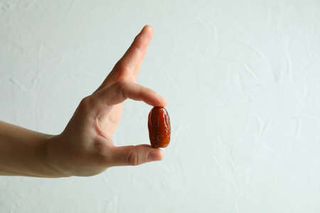 Female hand hold date fruit on white textured backgroundの写真素材