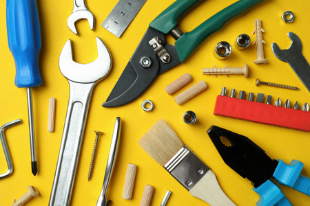 Different working tools on yellow background, close up