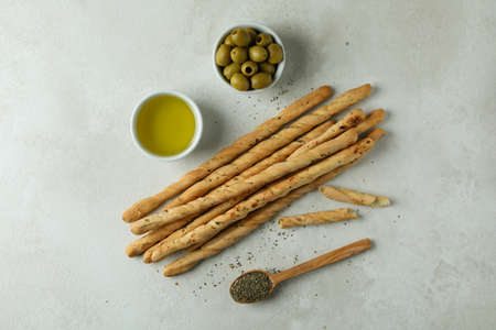 Grissini, olives, oil and spoon with spices on white textured backgroundの写真素材