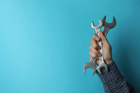 Male hand holds wrenches on blue backgroundの写真素材