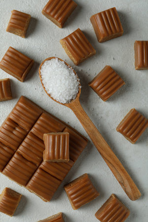 Caramel pieces and spoon with salt on white textured backgroundの写真素材