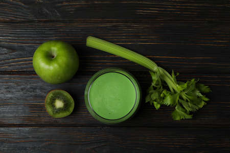 Glass of green smoothie and ingredients on wooden tableの写真素材