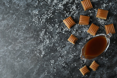 Salted caramel pieces and sauce on black smoky backgroundの写真素材