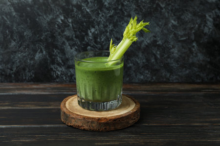 Glass of green smoothie with celery on board on wooden tableの写真素材