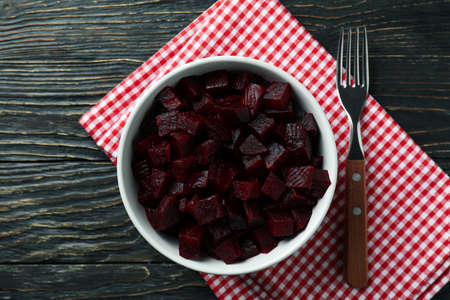Bowl with beet salad, fork and kitchen towel on wooden backgroundの写真素材